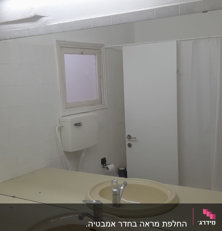 מראה גדולה מעל כיור בחדר אמבטיה